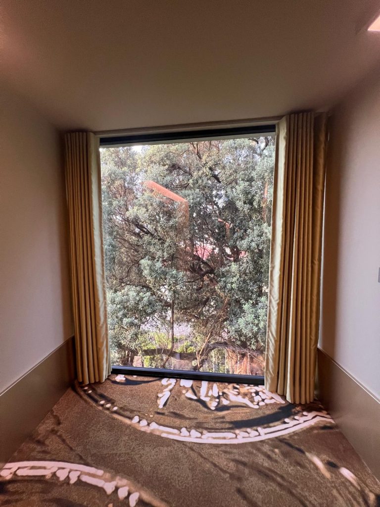 Photo of a large window at Vila Foz Hotel and Spa, offering a view of lush green vegetation outside. The window is framed by elegant interior decor, allowing natural light to filter through and create a tranquil atmosphere. The dense foliage outside includes vibrant greenery, adding to the serene and refreshing ambiance of the space.