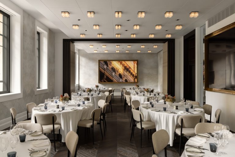 Elegant meeting room at Capella Sydney, featuring round tables set with pristine white linens, stylish beige chairs, and sophisticated lighting, perfect for hosting events or gatherings.