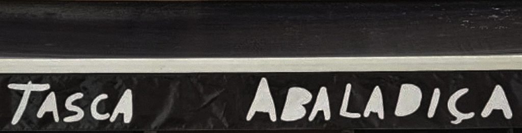 The exterior sign of Tasca Abaladiça, with the restaurant name hand-painted in white lettering on a dark background above the entrance.