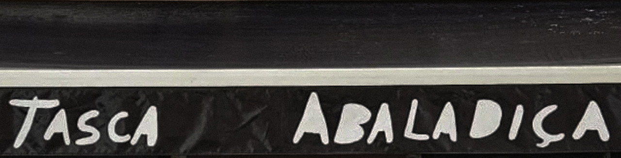 The exterior sign of Tasca Abaladiça, with the restaurant name hand-painted in white lettering on a dark background above the entrance.